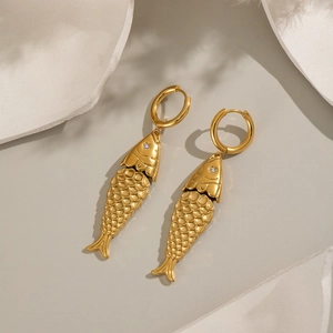 Elegant gold fish earrings with crystal eye accents displayed on a minimalist background