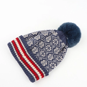 Detailed knit texture and snowflake pattern on warm winter beanie with navy pompom