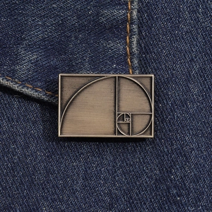 Detail of vintage bronze golden ratio spiral brooch pinned on dark blue denim fabric