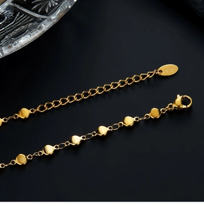 Macro shot of 18K gold plated chain with coin charms and K18 hallmark on the clasp tag