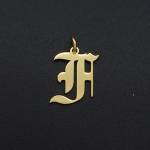 Macro shot of gold stainless steel letter H pendant with ring for DIY jewelry making
