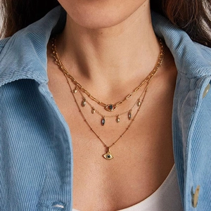 Three-layer gold necklace with evil eye pendant shown on a model in natural lighting