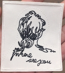 Detail of embroidered cloth patch with black line art and where are you text