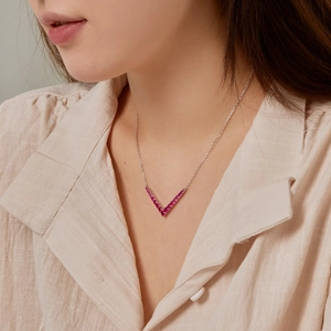 Detail view of S925 silver V-shaped necklace with inlaid ruby colored gemstones on model