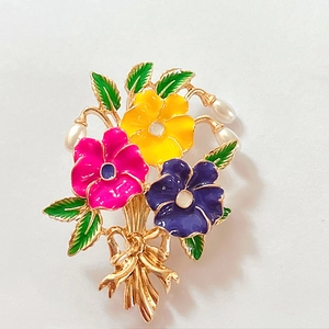 Detailed view of enamel flower brooch with pearl drops and a golden ribbon bow