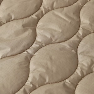 Macro shot of warm khaki quilted ripstop fabric with wave stitching and fine texture