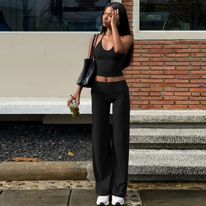 Détail d'un ensemble top dos nu noir et pantalon large dans un décor de style urbain