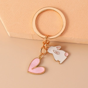 Detailed view of golden keychain with white enamel rabbit and pink pearl heart charms