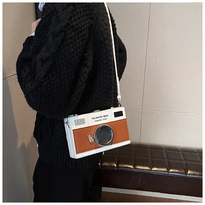 Detail of creative camera-shaped crossbody bag featuring white and brown patchwork design