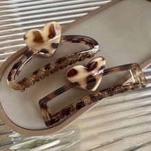 Detail of leopard print hair clips with heart accents on a beige ceramic tray