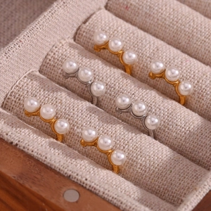 Detail view of triple white pearls set on gold and silver rings in a linen jewelry box