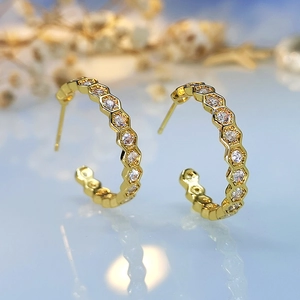 Detailed close-up of 18K gold-plated hexagonal honeycomb earrings with pavé white zircons