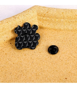 Macro view of black enamel pin back with geometric texture and rubber clutch closure
