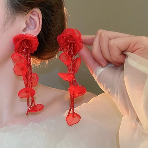 Detail of red fabric flower earrings with long pearl tassel fringe on model's ear