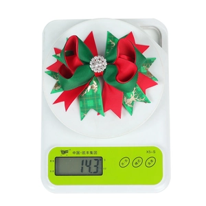 Detail view of a Christmas hair clip showing 14.3g weight on a digital scale