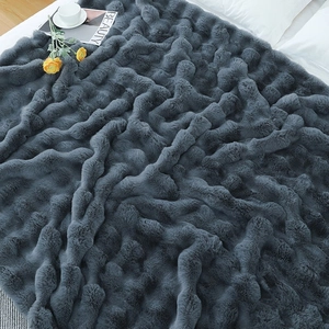 Close-up detail of dark grey faux fur plush blanket draped on a cozy white bed