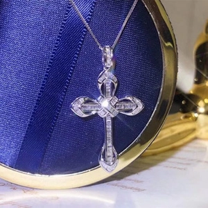 Close-up of luxury silver cross necklace with emerald-cut and round crystal stones