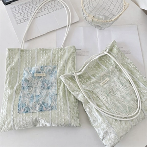 Detail of light green velvet tote bag with white lace embroidery and fabric pocket detail