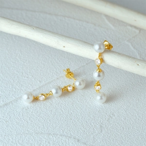 Detailed shot of long S925 silver tassel earrings featuring white pearls and cubic zirconia