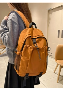 Seitenansicht des orangefarbenen Nylon-Rucksacks mit verstellbaren Riemen und Netztaschen