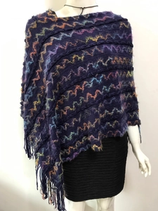Détail d'un poncho en maille marine avec motifs ondulés colorés et longues franges