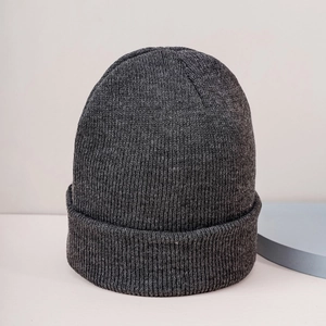 Close-up detail of dark grey knit beanie showing ribbed texture and folded cuff