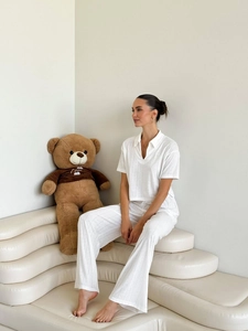 Cozy white knit lounge set with V-neck top and wide-leg trousers on a modern sofa