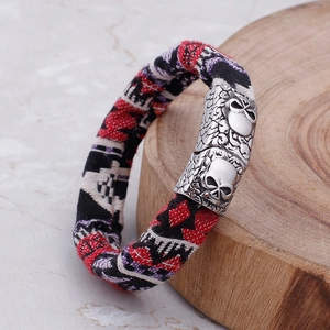 Close-up of tricolor woven canvas strap with silver skull charm on marble surface