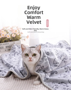 Close-up of a thick grey flannel pet blanket with dark paw prints wrapped on a silver cat