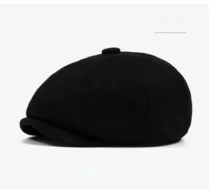 Detailed view of black wool newsboy cap featuring a top button and textured fabric