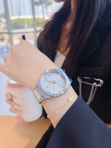 Close-up of silver stainless steel watch with white dial and gold chain bracelet set