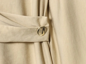 Macro detail of irregular gold button on khaki twill fabric shirt and pants set