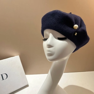 Detail of navy wool beret with large pearl and gold bead on an artistic model head