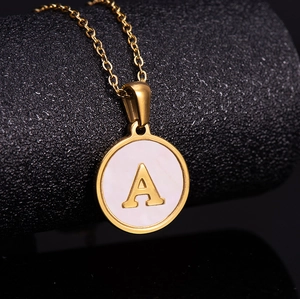 Macro detail of 18K gold plated stainless steel necklace with pink shell letter A pendant