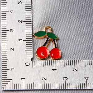 Macro view showing dimensions of a red cherry pendant with green leaves for jewelry making