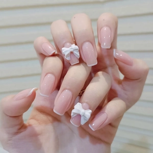 French tip press-on nails in nude pink with 3D white bow charms and glossy finish