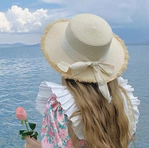 Elegant beige raffia sun hat with frayed edge and bow detail, seaside vacation style