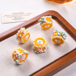 Detailed view of dessert-themed resin beads with cream flowers and bows on a tray