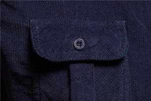 Macro detail of dark blue corduroy shirt featuring pocket and branded button texture