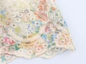 Détails de broderie florale et dentelle ajourée sur cette robe d'été blanc cassé