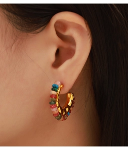 Detailed close-up of a gold C-shaped earring featuring vibrant colorful natural beads