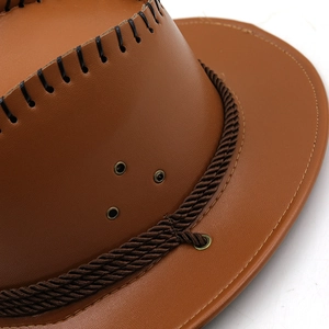 Detail of a brown cowboy hat featuring faux leather texture and metallic ventilation eyelet