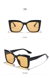 Detail view of bold black square cat-eye sunglasses with retro yellow amber lenses