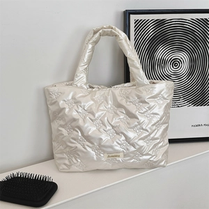Close-up of pearl white quilted puffer tote bag with bow patterns and brand label