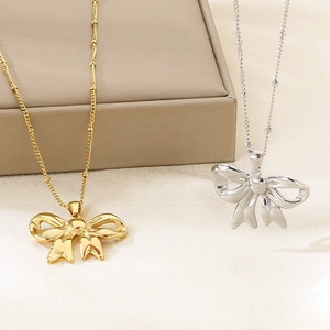 Hollow bow necklace set in gold and silver finish on elegant display stand