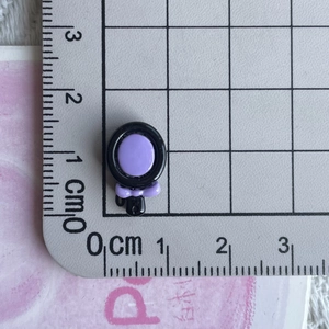 Detail of a dark black and purple heart charm with a bow on a metric measuring ruler