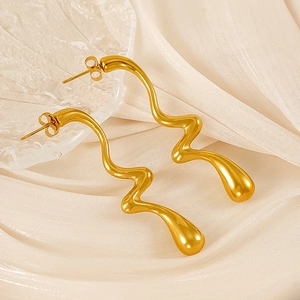 Detailed view of polished gold wavy curve stud earrings on elegant pleated silk fabric