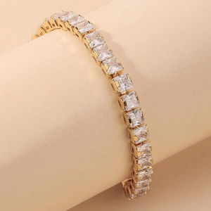 Detail of a gold tennis bracelet featuring princess cut square cubic zirconia stones
