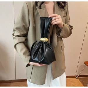 Detail showing black ruched leather handbag with iconic gold pebble-shaped metal clasp