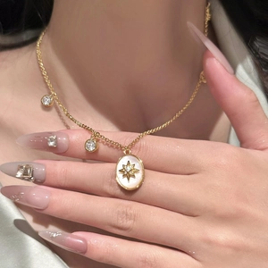 Close-up of gold vintage cross necklace with mop inlay and cubic zirconia on model